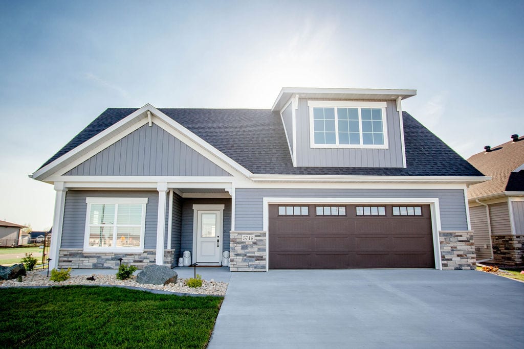 A front home exterior with light blue siding and stone detailing on the bottom.